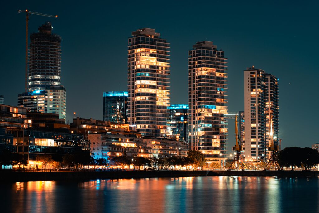 Night view of a vibrant urban skyline with skyscrapers reflecting on a river.